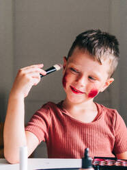Charmantes Kind mit Make-up-Applikator schaut weg auf den Tisch mit Lidschatten-Palette - ADSF30432