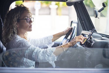 Mature woman wearing eyeglasses using global positioning system on smart phone while sitting in car - SIPF02412