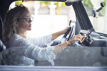 Reife Frau mit Brille, die im Auto sitzend ein globales Positionierungssystem auf einem Smartphone nutzt - SIPF02412