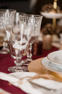 Kristallgläser mit Besteck in der Nähe von Tellern auf einem festlich gedeckten Tisch für ein Weihnachtsessen - ADSF30502