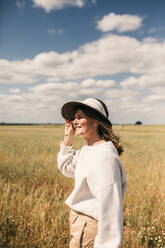 Lächelnde reife Frau mit Hut auf einem Feld - GRCF00915