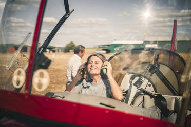 Lächelnde Frau mit Kopfhörern in einem Propellerflugzeug - GRCF00928