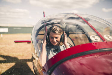 Lächelnde reife Frau beim Piloten an einem sonnigen Tag - GRCF00930