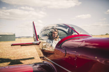 Smiling mature woman piloting airplane during sunny day - GRCF00935