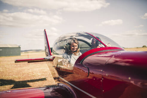 Lächelnde reife Frau, die an einem sonnigen Tag ein Flugzeug steuert - GRCF00935