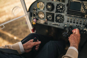 Männlicher Pilot, der das Bedienfeld in einem Flugzeug bedient - GRCF00936