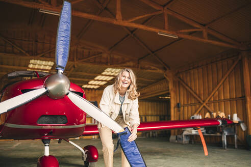 Fröhliche Frau, die den Fächer eines Flugzeugs bedeckt - GRCF00948