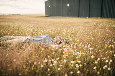Frau entspannt sich inmitten von Pflanzen auf einem Feld - GRCF00958