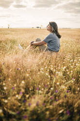 Frau, die auf einem landwirtschaftlichen Feld sitzt und träumt - GRCF00965