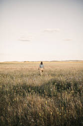 Woman walking amidst plants at agricultural field - GRCF00975