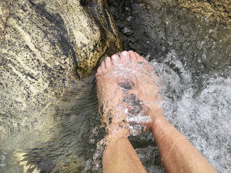 Bare feet of adult woman enjoying cold river water - GWF07169