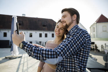 Lächelndes Paar nimmt Selfie durch Smartphone in der Stadt - LLUF00105