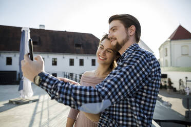 Smiling couple taking selfie through smart phone in city - LLUF00105