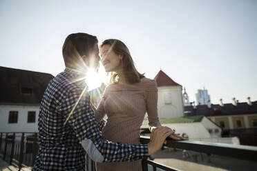 Affectionate couple embracing each other while standing on rooftop - LLUF00107