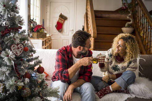 Happy couple toasting with coffee at home during Christmas - SIPF02425