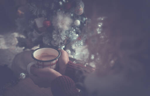 Frau hält Kaffeetasse zu Hause während Weihnachten - SIPF02434