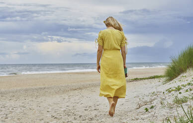 Blonde Frau geht am Strand spazieren - AZF00378