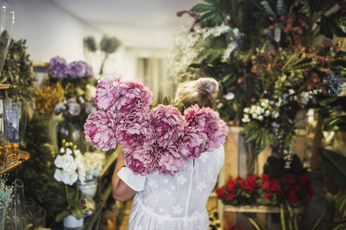 Blumenhändlerin mit rosa Blumenstrauß bei der Arbeit im Geschäft - GRCF00988