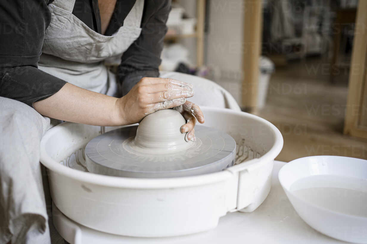 Female potter molding clay on pottery wheel in workshop stock photo