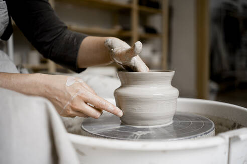 Young craftswoman making flower pot on pottery wheel - RCPF01319