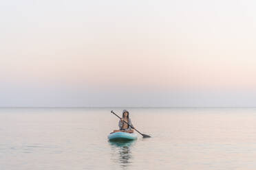 Junge Paddleboarding auf dem Meer bei Sonnenuntergang - EYAF01772