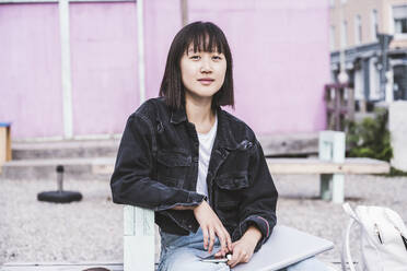 Female teenager with laptop sitting on bench - UUF24719