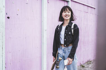 Teenager-Mädchen mit Skateboard an der Wand - UUF24733