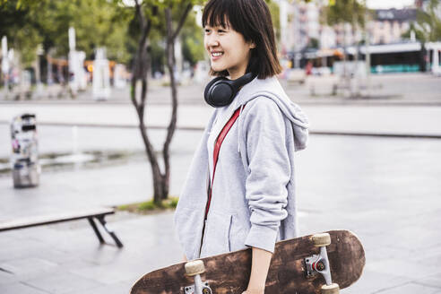 Weiblicher Teenager mit Skateboard auf dem Gehweg - UUF24751