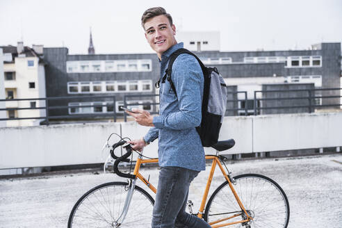 Mann mit Rucksack zu Fuß mit Fahrrad in der Stadt - UUF24768