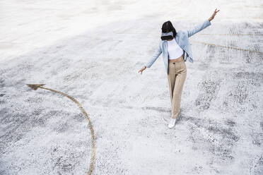 Teenagerin benutzt Virtual-Reality-Headset auf dem Dach eines Parkhauses - UUF24793