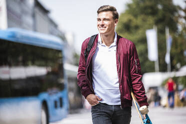 Lächelnder Mann beim Gehen mit der Hand in der Tasche - UUF24838