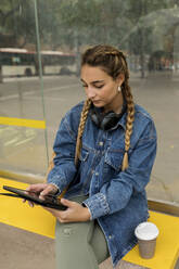 Frau benutzt digitales Tablet an der Bushaltestelle - VABF04397