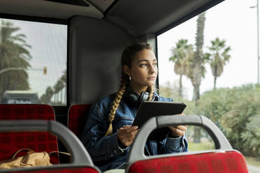 Junge Frau mit digitalem Tablet im Bus sitzend - VABF04402