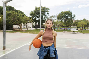 Junge Frau mit Basketball auf dem Sportplatz - VABF04411