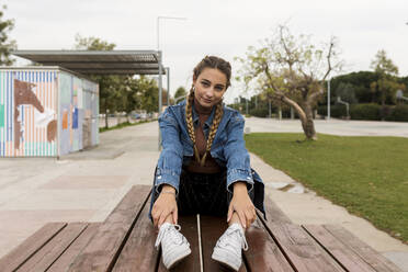 Young woman sitting on bench at park - VABF04414