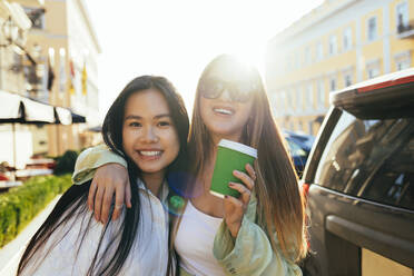 Smiling female friends with long hair during sunny day - OYF00534