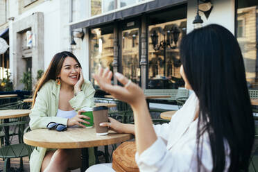 Freundinnen mit Kaffeetasse im Gespräch in einem Straßencafé - OYF00537
