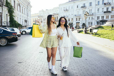 Weibliche Freunde mit Einkaufstaschen zu Fuß in der Stadt Straße - OYF00563