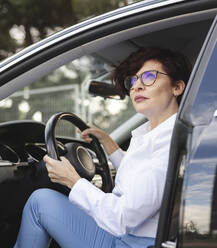 Berufstätige Frau hält Lenkrad, während sie im Auto sitzt - JCCMF04046