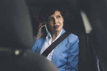 Reife Geschäftsfrau, die im Auto sitzend mit ihrem Handy telefoniert - JCCMF04051