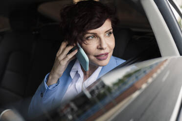 Schöne weibliche Fachkraft, die im Auto mit einem Smartphone spricht - JCCMF04052