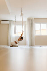 Sportlerin macht Aerial Yoga im Studio - OCAF00769