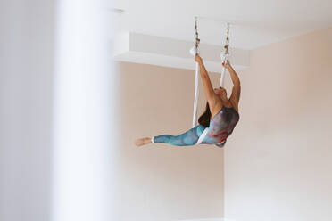 Sportlerin bei Dehnungsübungen während des Aerial Yoga im Studio - OCAF00775