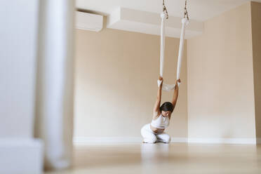 Sportlerin übt Aerial Yoga im Studio - OCAF00779