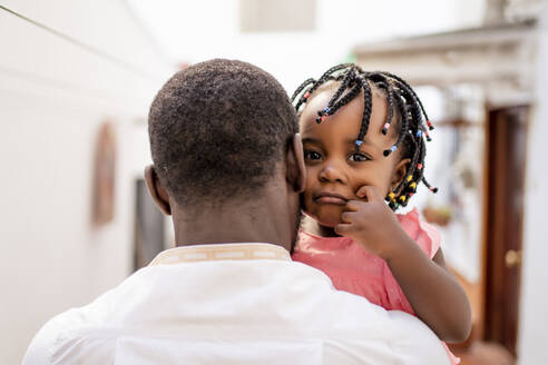 Man carrying sad daughter with braided hair - OCMF02249