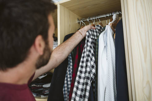 Mann nimmt zu Hause Kleidung aus dem Kleiderschrank - EBBF04587