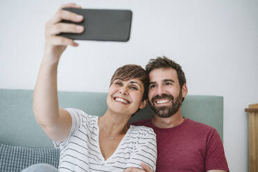 Lächelndes Paar nimmt Selfie durch Smartphone zu Hause - EBBF04605