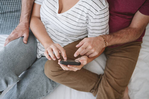 Mann und Frau benutzen Smartphone auf dem Bett zu Hause - EBBF04614