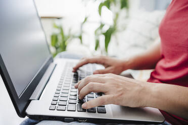 Frau beim Tippen auf einem Laptop zu Hause - EBBF04667