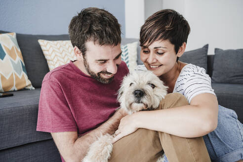 Mann und Frau spielen mit Hund zu Hause - EBBF04673